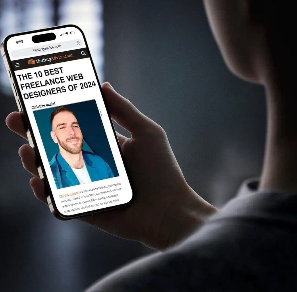 Individual holding a smartphone displaying an article about web designers with a photo of a man.